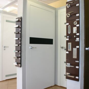 Białe drzwi z przeszklonymi elementami-wystawa oraz klamki